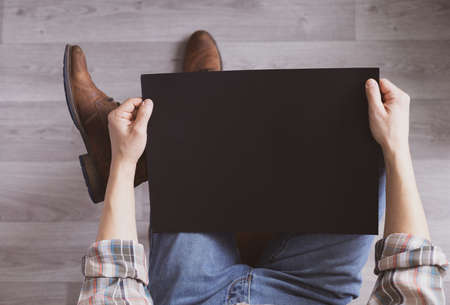 Men's hand holding black paper blank. Male hand and chalk paper, top viewの写真素材