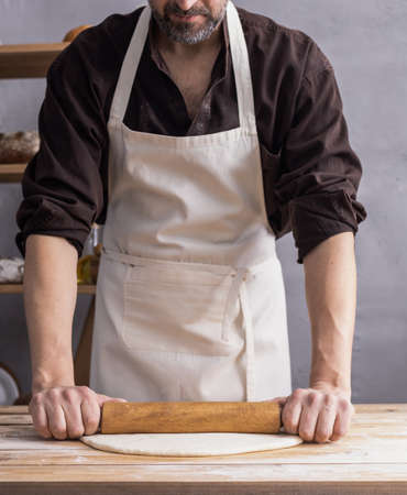 Baker man kneading or making dough or bread cooking. Bakery concept and wooden table background textureの写真素材