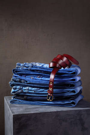 Denim jeans and jacket with belt at old cube near wall background texture. Modern casual style of classic jeans fashionの写真素材