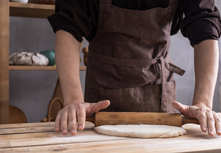 Baker man kneading or making dough or bread cooking. Bakery concept and wooden table background textureの写真素材