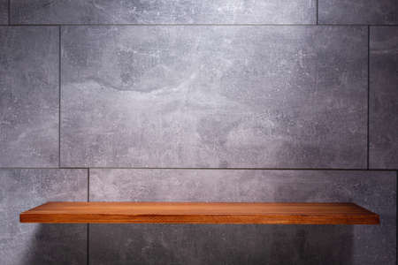 Wooden shelf at wall of stone or marble surface background tile texture.  Book shelf and grey wall background with copy spaceの写真素材