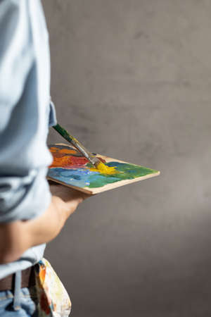 Man painter holding paint palette with paint brush. Young artist and paintbrush painting in creative studioの写真素材