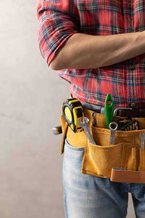 Man worker and tool belt near wall. Male hand and construction tools. Renovation or repair conceptの写真素材