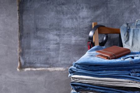 Denim jeans and leather wallet or bag at chair.  Stack of jeans near abstract background texture surfaceの写真素材