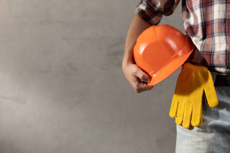 Man worker holding construction helmet near plater wall. Male hand and construction tools. Renovation or repair conceptの写真素材