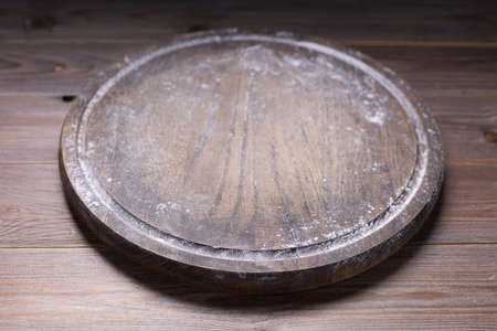 Pizza cutting board and wheat powder flour for homemade bread cooking or baking on table. Wooden tabletop background. Bakery concept in kitchenの写真素材