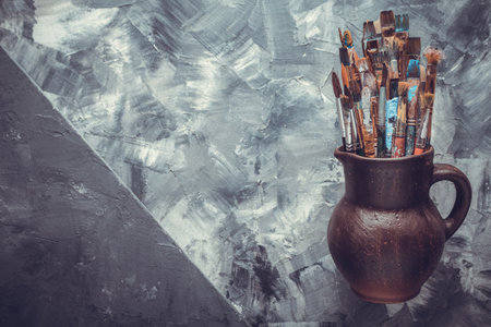 Paint brush in clay jug at  art painting canvas as abstract background texture. Paintbrush for painting for artistic paint still life. Abstract art conceptの写真素材