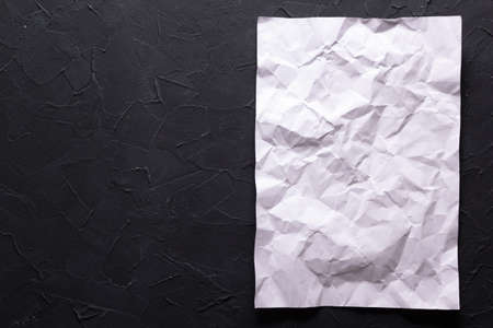 White wrinkled or crumpled paper at black abstract background texture