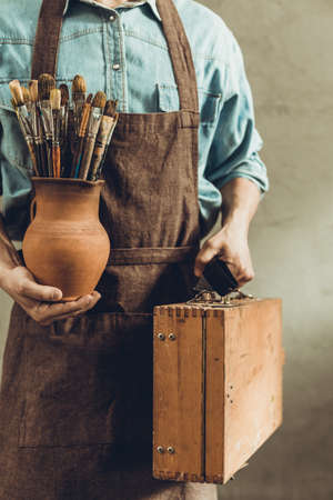 Man artist painter holding clay jug with paint brush. Painter artist and paintbrush in creative studio as art conceptの写真素材