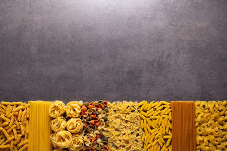 Raw pasta assortment at stone tabletop. Pasta collection food on table backgroundの写真素材