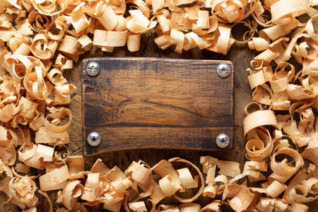 Wood shavings and name plate on table background. Wooden shaving at old plank board textureの写真素材