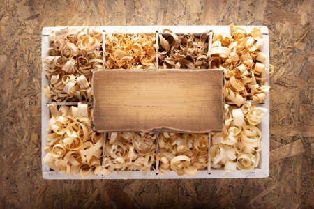 Wood shavings in box on table background. Wooden shaving at old plank board texture