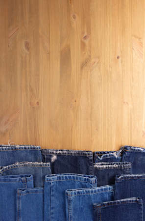 Blue jeans denim on wood table. Jeans heap at wooden background textureの写真素材