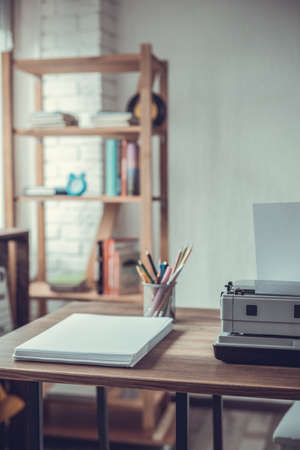 Stack of paper and vintage old typewriter at wooden desk table. Writer or screenwriter creative...
