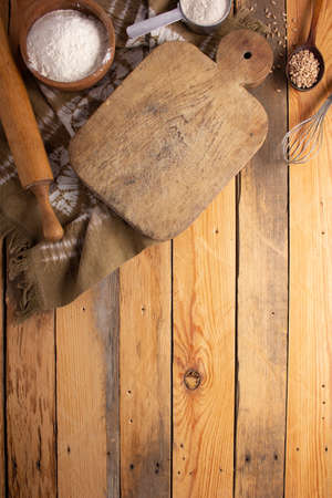 Cutting board and scattered flour powder at wood background top table. Bread cncept recipe