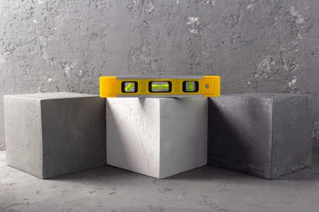 Concrete cube and construction level at brick on abstract background texture. Art or construction conceptの写真素材