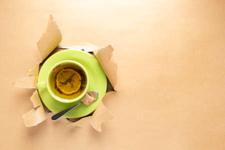 Cup of tea with lemon in torn paper. Mug full green teaの写真素材