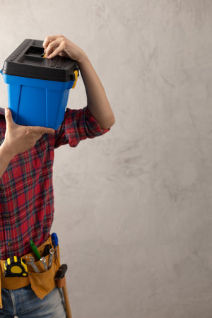 Worker man holding construction toolbox near concrete or cement wall. Male hand and tool box for house room renovation. Home renovation conceptの写真素材