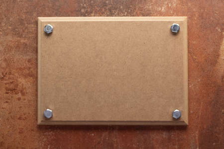 Wooden nameplate or sign board screwed on wall background. Front view of name plateの写真素材