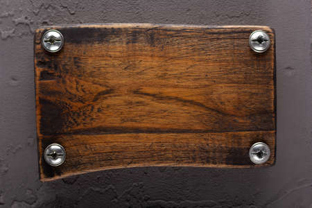 Wooden nameplate or sign board screwed on wall background. Front view of name plateの写真素材