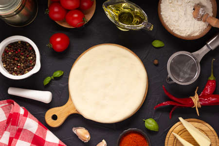 Pizza and dough homemade cooking with ingredients at table. Pizza with sauce on tabletop background. Recipe concept in kitchenの写真素材