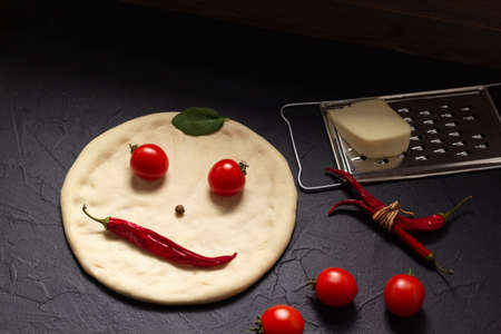Pizza dough and ingredients for homemade cooking at table. Recipe concept in kitchenの写真素材
