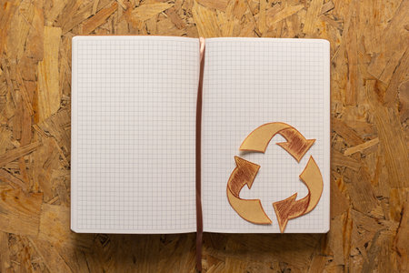 Notebook and recycle symbol at chipboard plywood background texture. Recycling concept or creative ideaの写真素材