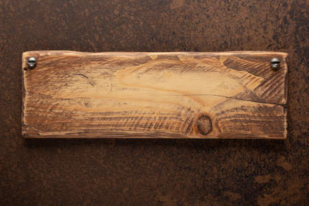 Wooden nameplate or sign board screwed on wall background. Front view of name plateの写真素材