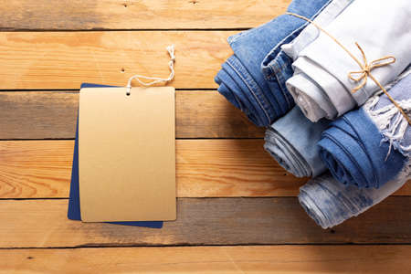 Jeans denim and price tag label at wooden background texture. Blue jeans denim fabric on tableの写真素材