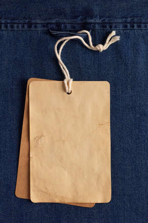 Paper price tag label at jeans background texture. Blue jeans denim fabric