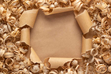 Wood shavings on torn paper background. Wooden shaving at cardboard textureの写真素材