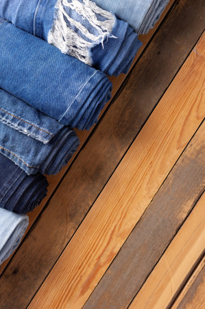 Jeans heap at wooden background texture. Blue jeans denim fabric on tableの写真素材