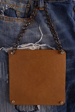 Wooden price tag label at jeans background texture. Blue jeans denim fabricの写真素材