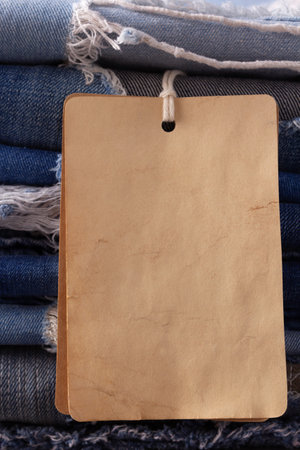 Blue jeans denim heap at table background. Jeans fabric material and tag price labelの写真素材