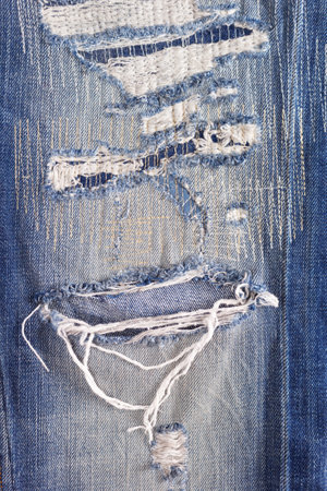 Torn jeans denim background texture. Blue jeans fabric closeup as material surfaceの写真素材