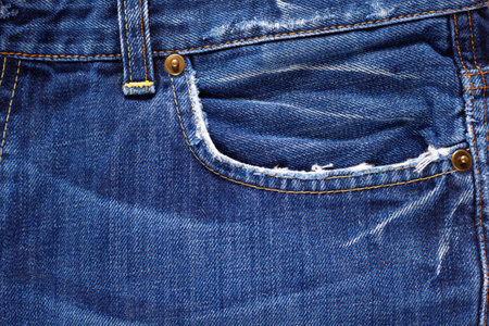 Torn jeans pocket denim background texture. Blue jeans fabric closeup as materialの写真素材