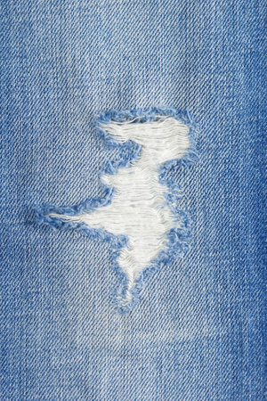 Torn jeans denim background texture. Blue jeans fabric closeup as material surfaceの写真素材