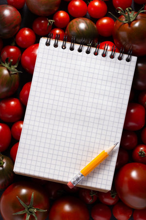Cookbook and fresh tomato at table. Tomatoes with recipe book on tabletop top viewの写真素材