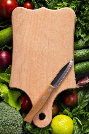 Variety of fresh vegetables and wood cutting board on table background. Cookig concept and salad ingredients at tabletop top viewの写真素材