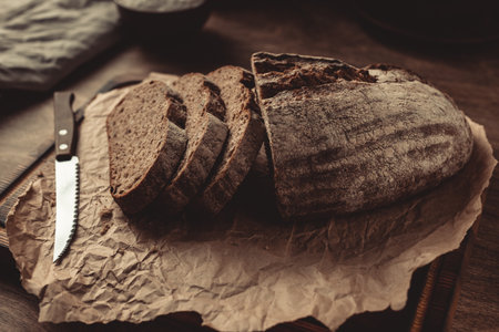 Homemade bread with parchment paper on wood table. Bread at wooden tabletop as baking conceptの写真素材