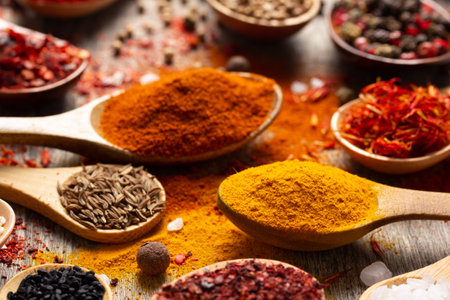 Paprika, pepper and turmeric spice in spoon on table background. Variety of spices and ingredients at kitchen table closeupの写真素材