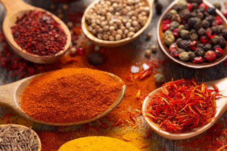 Paprika, pepper and turmeric spice in spoon on table background. Variety of spices and ingredients at kitchen table closeupの写真素材