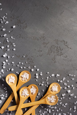 scattered crystal sea salt in spoon on concrete stone table background. Cooking food ingredients at kitchen table top viewの写真素材