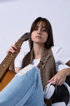 Young woman holdilng acoustic guitar. Musician sitting in studio with classic guitarの写真素材