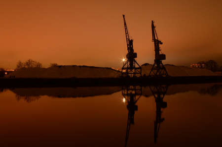 port cranes on the city pier at night