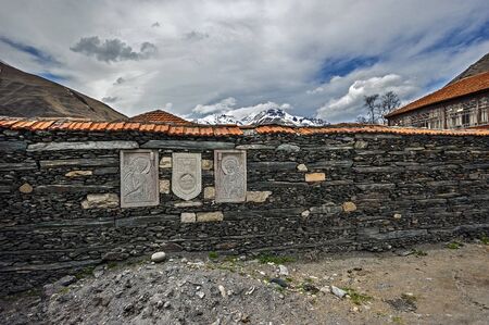 Georgia, the Georgian Military Road , the village of Sno . Stone wall of the village cemetery with images of saints , hewn on stone slabs .のeditorial素材
