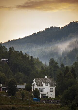 Norway, early in the morning in a small village on the banks of Neroyfiord , fog in the mountains . Wooden house.のeditorial素材