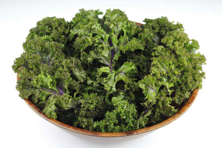 Wood bowl of red kale, green leaf with purple veins, on a white background.の写真素材