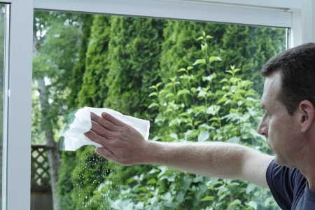 Adult male cleaning a clear glass sliding patio door with a paper towelの写真素材