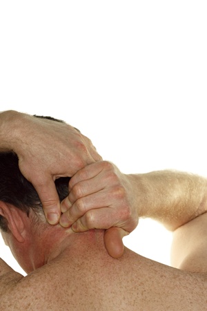 middle aged man seen from behind rubbing his neck with his hands in front of a white background.の写真素材